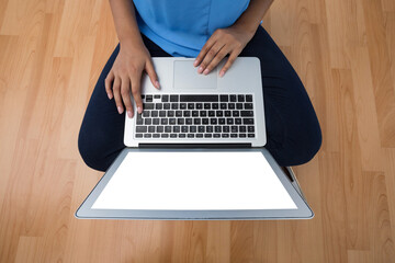 Mid section of female executive using laptop while sitting on wooden floor - Powered by Adobe
