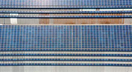 Drop down view of solar power plant with panels placed on industrial roof tops.