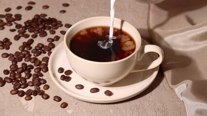 Coffee with milk on beige concrete background with coffee beans, aesthetic concept. Milk poured in cup of fresh coffee