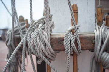 Fototapeta na wymiar several thick cotton ropes lashed off at a common point on the main deck of a historic sailing ship that requires a large crew of skilled sailors to leave port and go on a voyage