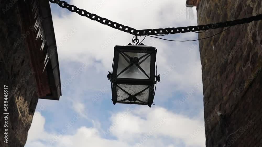 Poster ancient lantern on a chain in the walls of the castle