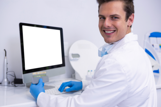 Portrait of dentist working on computer against wall