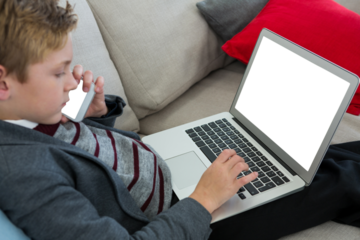 HIgh anlge view of boy using laptop on sofa