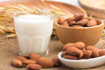 Almond milk in glass with almonds on wooden table