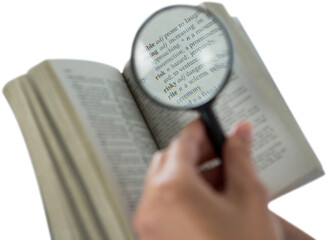 Businesswoman reading dictionary through magnifying glass