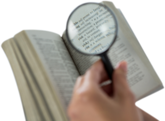 Businesswoman reading dictionary through magnifying glass