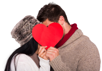 Young couple kissing behind red heart