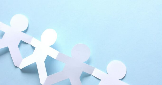 Close up of people holding hands made of white paper on blue background with copy space