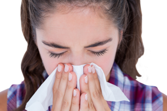 Close-up of sick woman sneezing in a tissue
