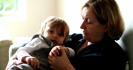 Baby leaving grandmother lap, multi generation family in couch