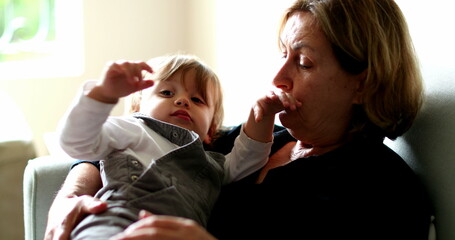 Baby leaving grandmother lap, multi generation family in couch