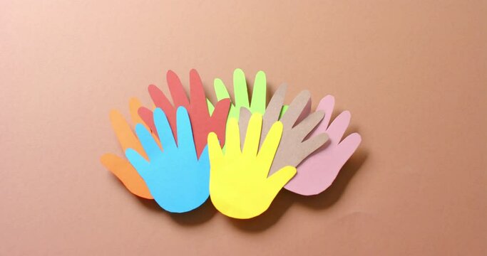 Close up of hands together made of colourful paper on brown background with copy space