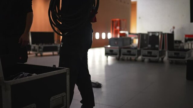 Male, sound engineer, puts the cables in a black hard case.
