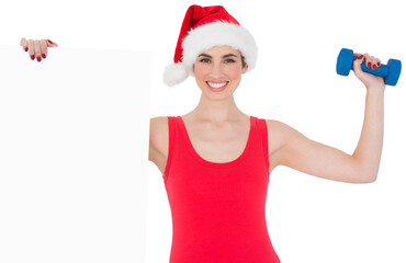 Festive fit brunette holding page and dumbbell