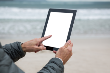 Man using digital tablet on beach