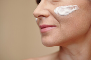 Nourishing cream on face of mature woman