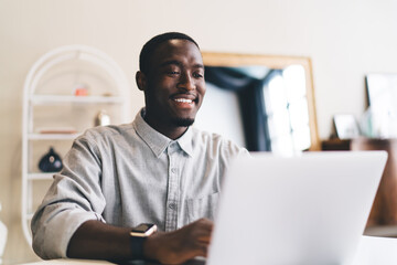 Cheerful African American man browsing laptop