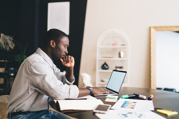 Thoughtful African American man using laptop at home office
