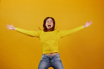 girl in a yellow sweater rejoices on a yellow background