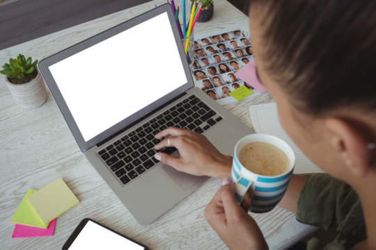 Female photo editor holding coffee cup while using laptop - Powered by Adobe