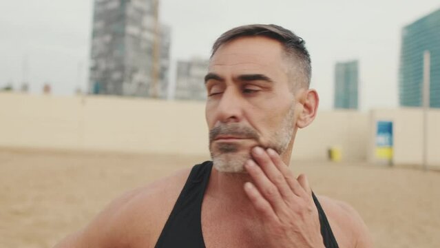 Man works out in the beach and stretches the neck muscles 