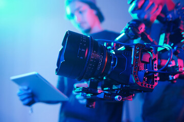 Close-up of operator using professional camera during shooting with director controlling the process