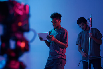 African American young operator examining project on digital tablet before shooting in studio