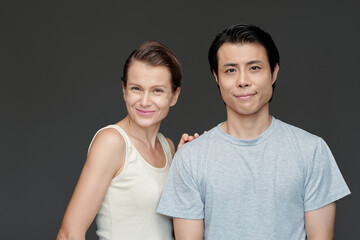 Studio portrait of diverse couple with age difference smiling at camera