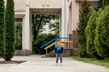 Little first grader with backpack looking the copybook, going home from school