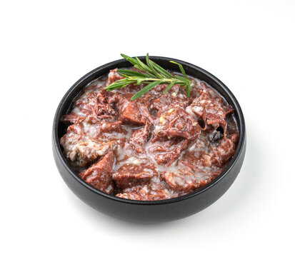 Canned Beef Or Lamb Stew In A Black Bowl With Rosemary On A White Isolated Background.