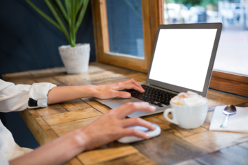 Cropped hands of woman using laptop at table