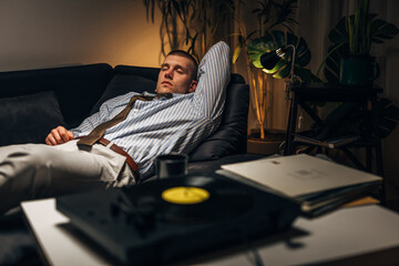 A young businessman enjoys listening to records after a hard day at work