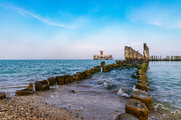 Old ruined wooden pier and a sandy beach	