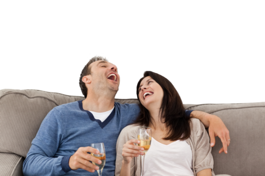 Couple laughing while drinking champagne on the sofa  - Powered by Adobe