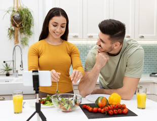 Couple making dinner together at home, watching food blog online