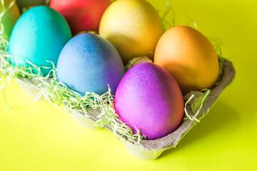 Fototapeta na wymiar Vibrant colorful easter eggs in a basket on a yellow background