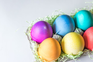 Vibrant colorful easter eggs in a basket on a white background