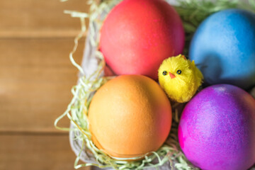 Fototapeta na wymiar Overhead Angle of Colorful vibrant easter eggs and a yellow chick in a nest 
