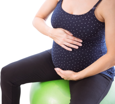Pregnant woman holding belly while sitting on exercise ball