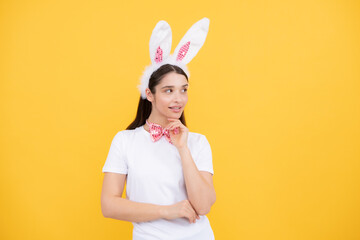 Obraz na płótnie Canvas Portrait of young girl with rabbit bunny ears isolated on yellow background. Easter bunny woman looks fun.