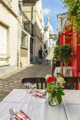 Fototapeta na wymiar Table in outdoor cafe waiting for the clients on the narrow pedestrian street in Paris, France. Blurred background.