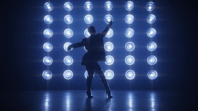 Silhouette of professional RnB dance performer moving hips at bright colorful strobing lights. Stylish dancer in trendy outfit performing at concert in Night Club. Night lifestyle, party concept shot