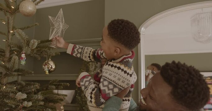 Father lifting son to put the star on the Christmas tree