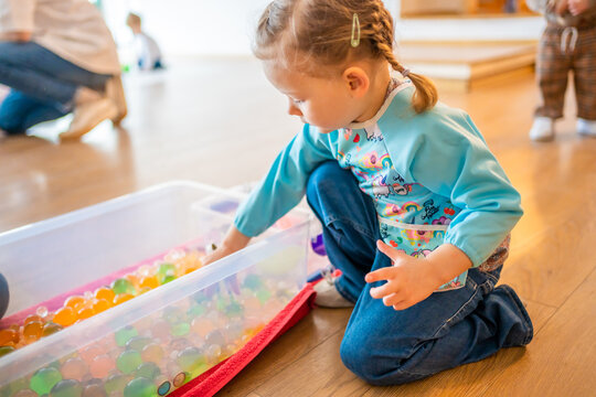 Little girl playing with sensory water beads, hydrogel balls. Sensory development and experiences, themed activities with children, fine motor skills development