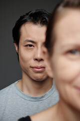 Obraz premium Japanese man standing behind mature woman and looking at camera, society concept