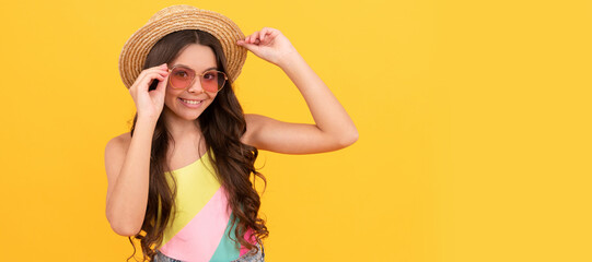 happy kid in summer straw hat and glasses has curly hair on yellow background, summer fun. Child face, horizontal poster, teenager girl isolated portrait, banner with copy space.
