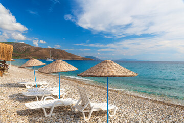 Sun loungers and umbrellas on Palamutbuku beach in Datca Peninsula, Mugla region, Turkey on Aegean sea