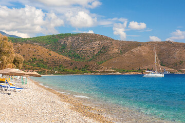 Fototapeta na wymiar Turkey summer resort with pebble beach and yacht. Palamutbuku beach in Datca Peninsula, Mugla region, Turkey