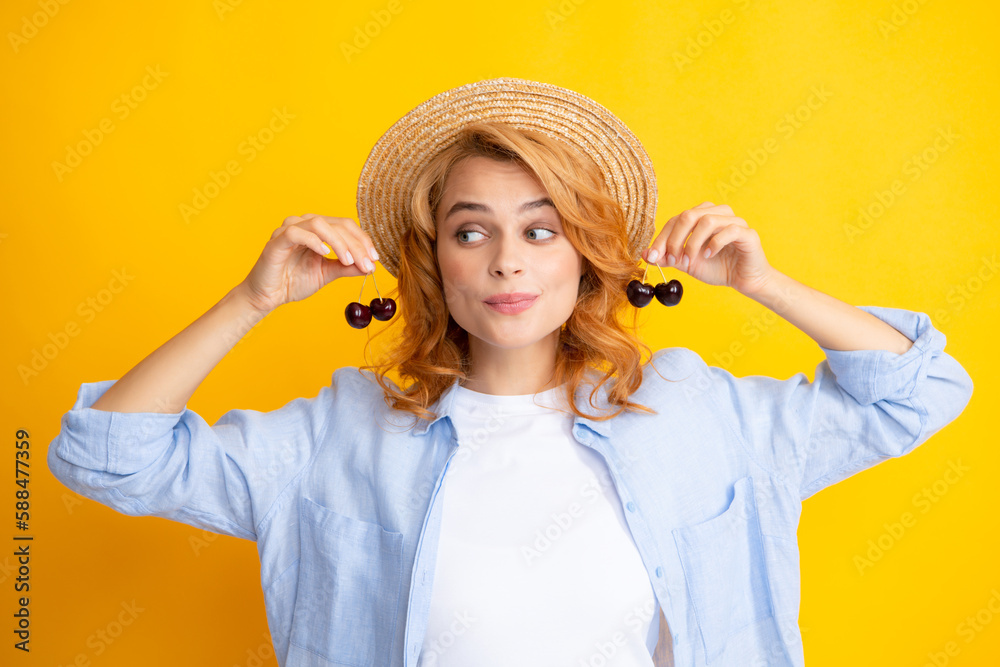 Wall mural Portrait of woman with cherries on yellow studio isolated background.