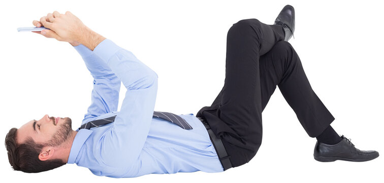 Cheerful businessman lying on floor using tablet